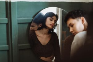 Two people sharing a reflective moment, captured through a mirror in an intimate setting.