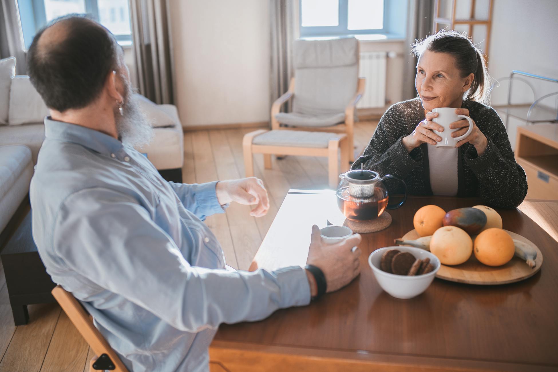 A senior couple having a relaxed morning with tea and fruits in a cozy living room.