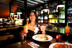 A woman enjoys a festive dinner with cocktails and sparkler in an Istanbul bar.