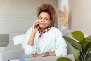Young woman smiling while talking on the phone, sitting comfortably on a couch indoors.
