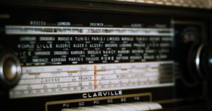 The dial of a 1957 Clarville radio, with station names printed across the glass