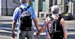 An older couple walking outdoors and holding hands