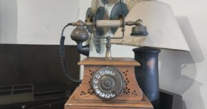 An antique rotary dial telephone on a wooden stand