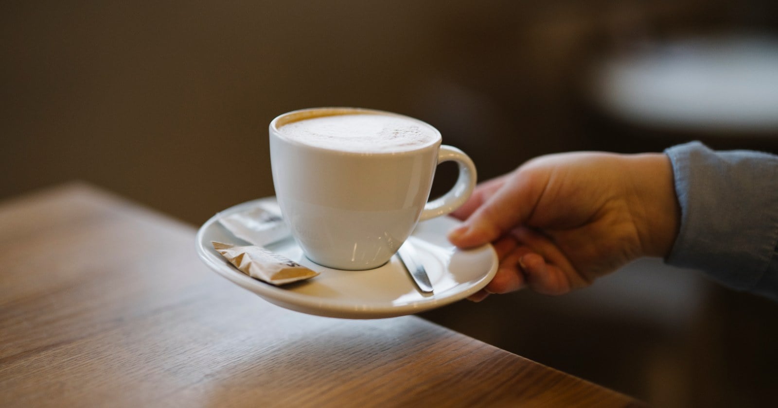 A warm cup of coffee in a white cup on a wooden table.