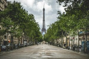 A picturesque view of the Eiffel Tower lined by trees and classic Parisian architecture.