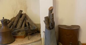 A rustic home hearth with stacked firewood and copper pots