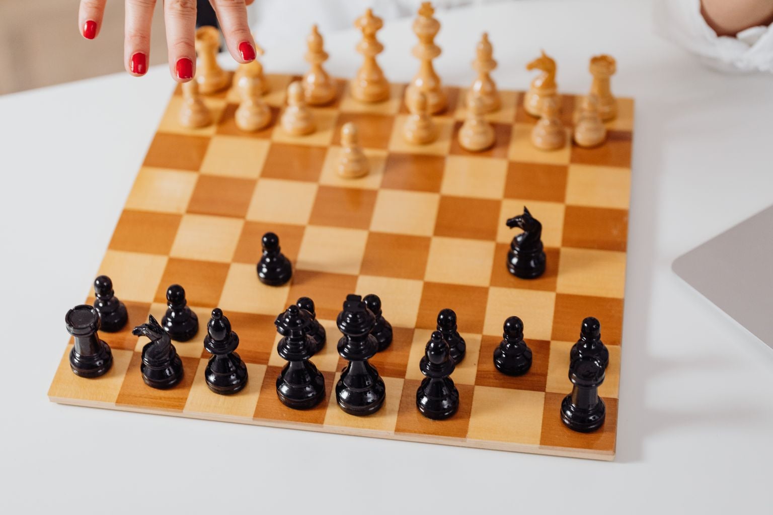 Close-up of a chessboard with pieces in action and a hand moving a piece