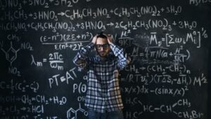 Man in glasses focusing on math problems on a chalkboard