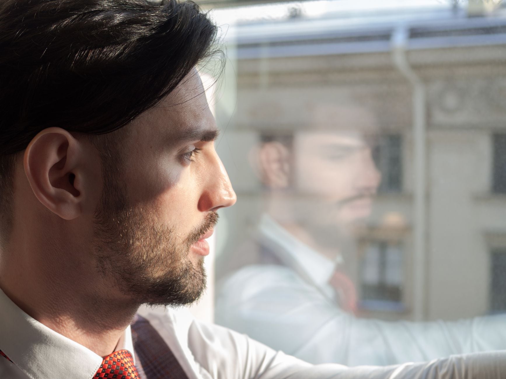 Profile of a businessman gazing through the window, contemplating his next move.