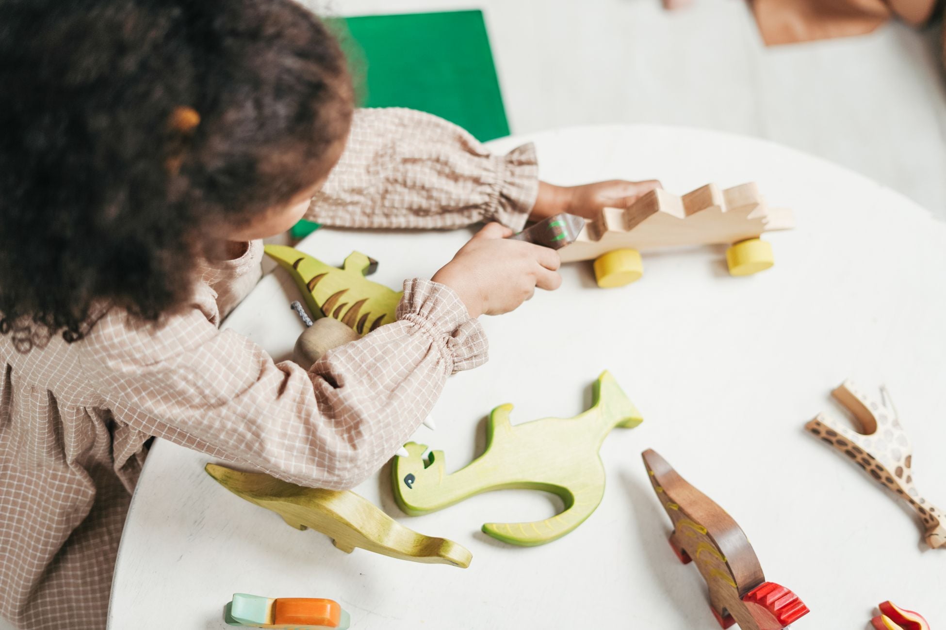 A young girl engaged in imaginative play with colorful wooden toys indoors.
