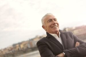 An older adult smiling warmly outdoors