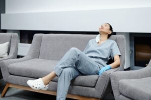 A nurse in scrubs takes a break, resting on a comfy hospital couch after a long shift