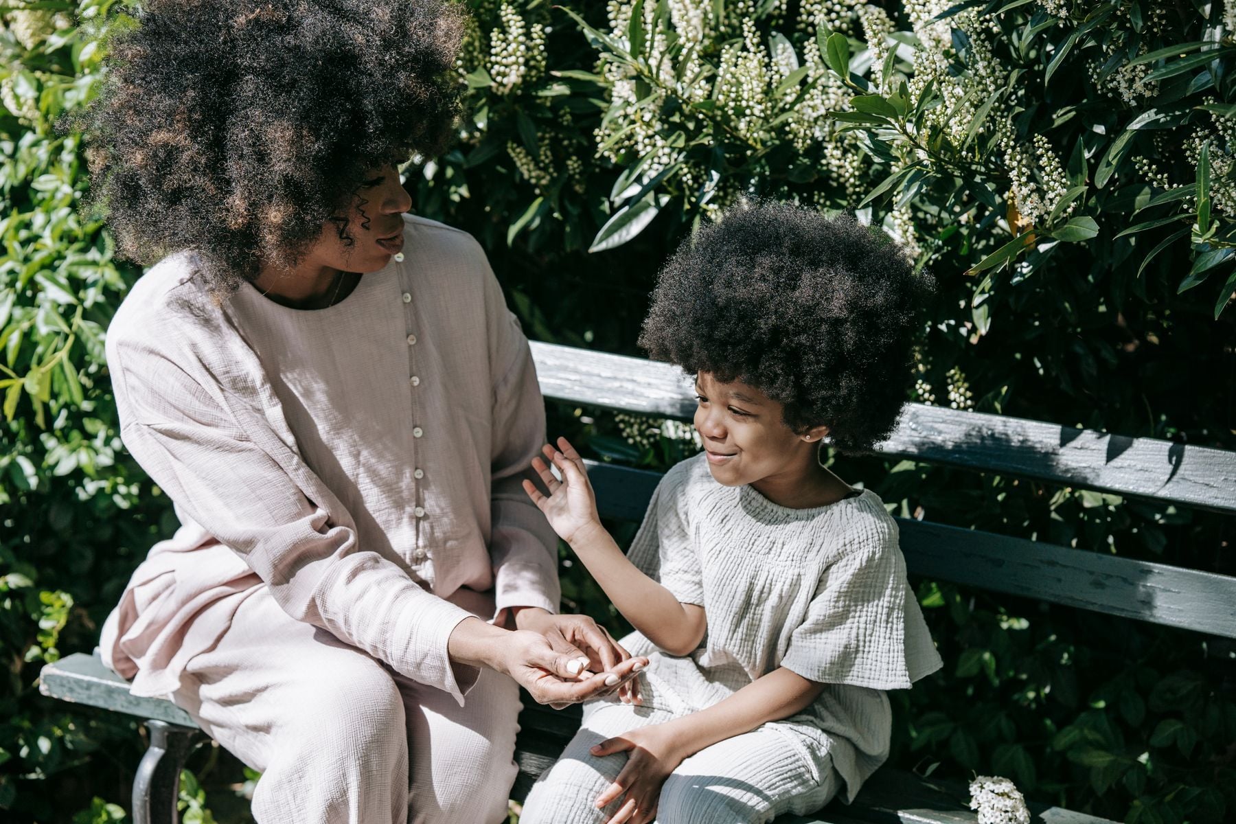 A mother and daughter having a calm conversation on a park bench, representative image