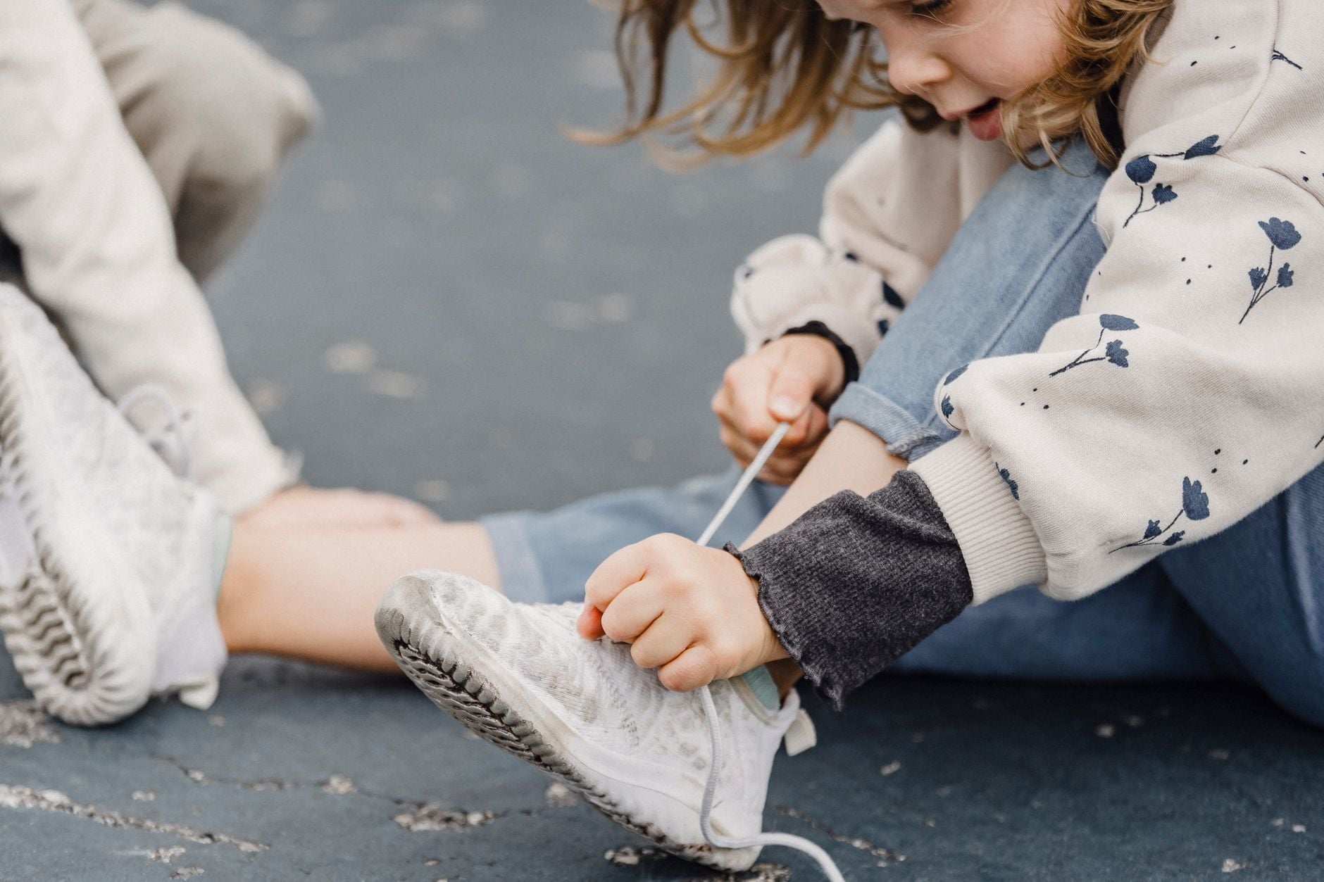 A young girl independently tying the laces on her sneakers.
