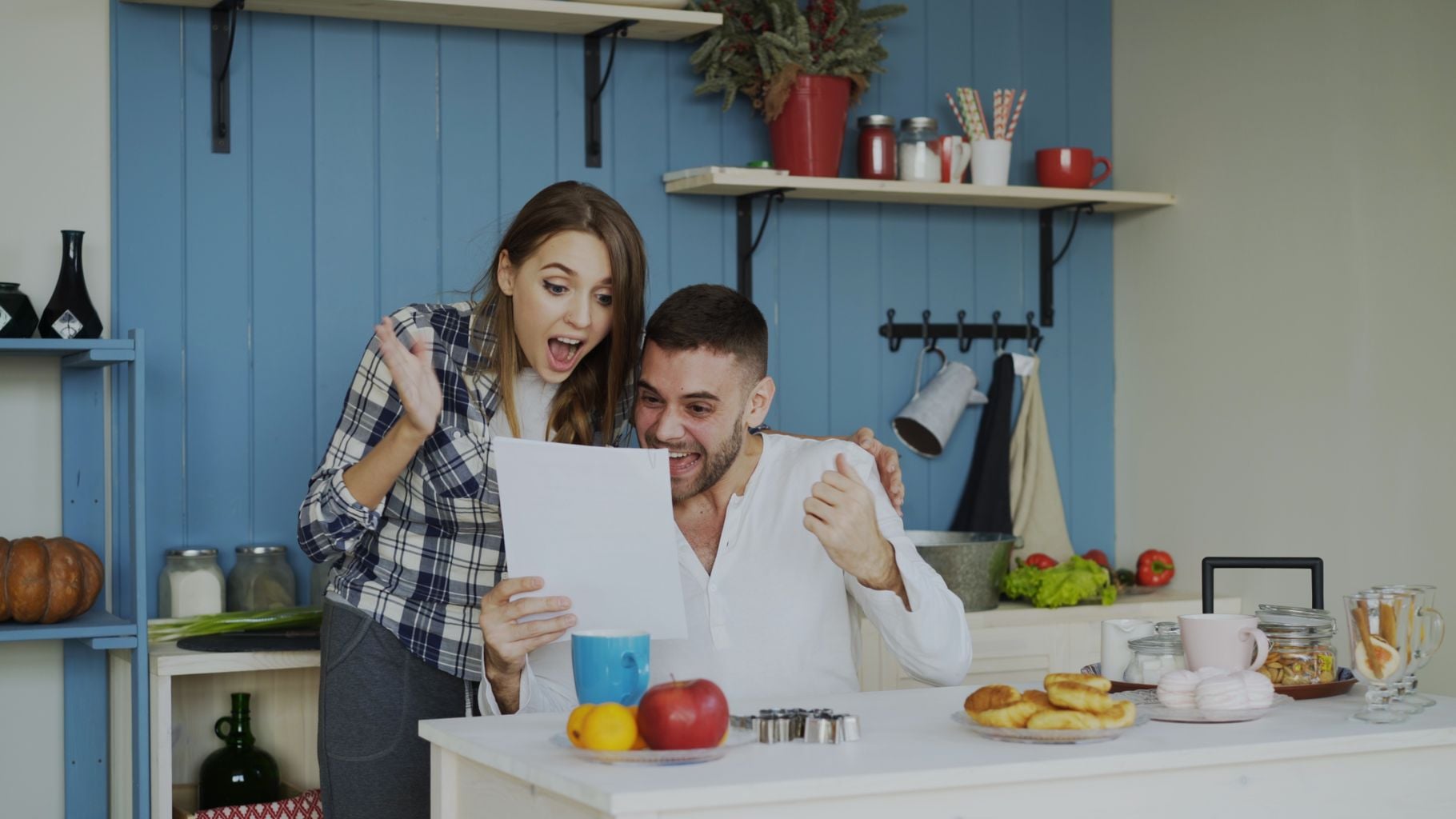 Happy couple celebrating good news together in a cozy kitchen setting