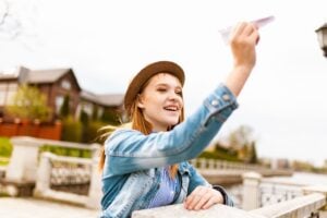 Smiling young woman in a hat and denim jacket enjoying a sunny day outside