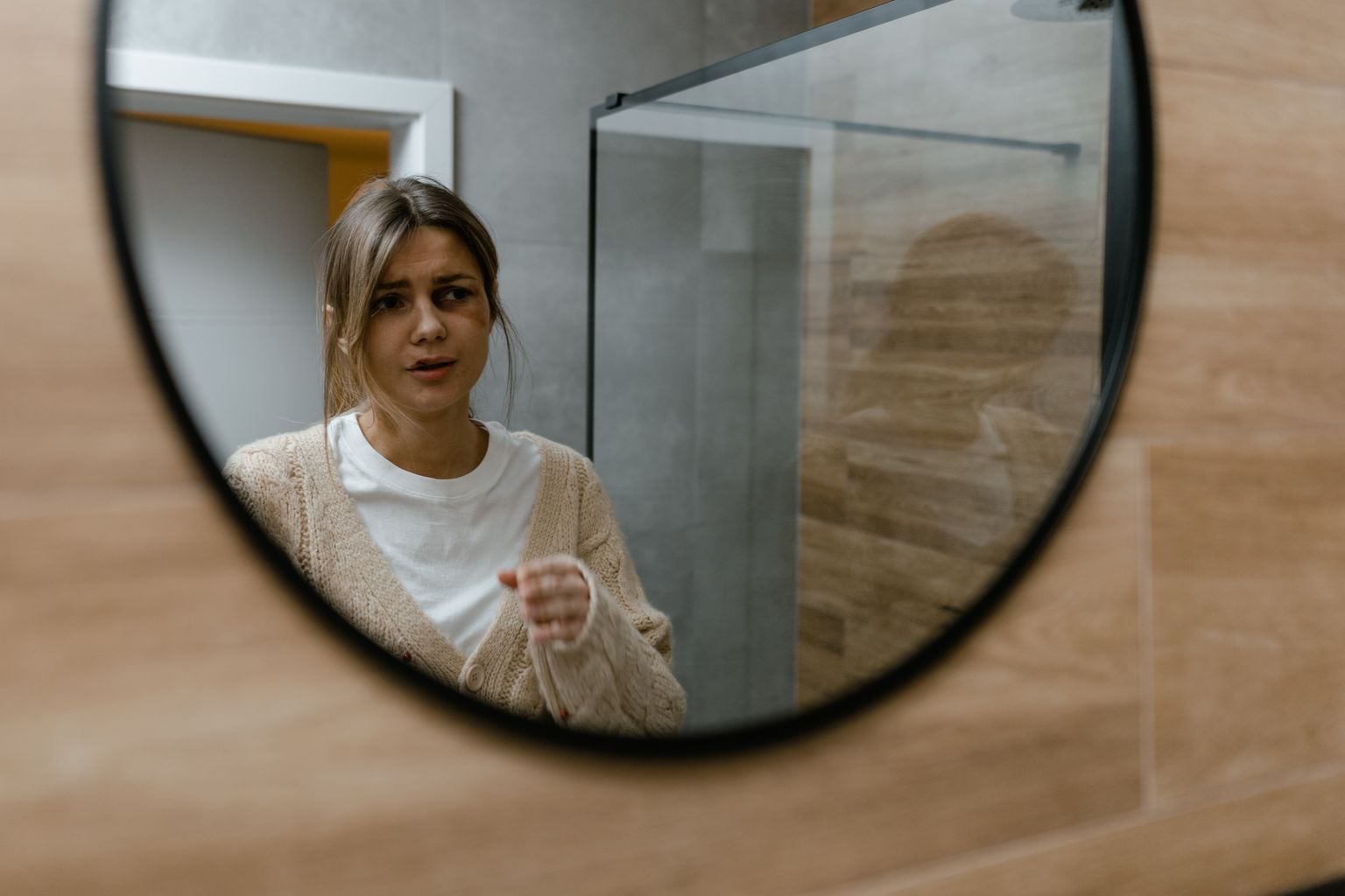 A woman gazes into a mirror, reflecting emotions and self-awareness